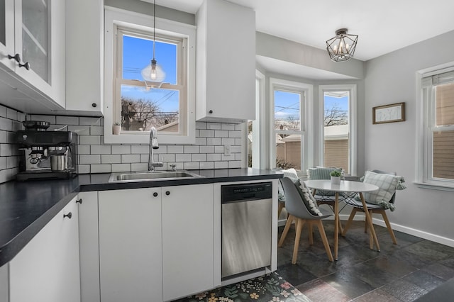 kitchen with dishwasher, dark countertops, a sink, and white cabinets