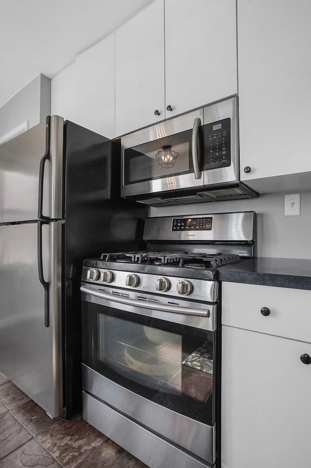 kitchen with appliances with stainless steel finishes, dark countertops, and white cabinets