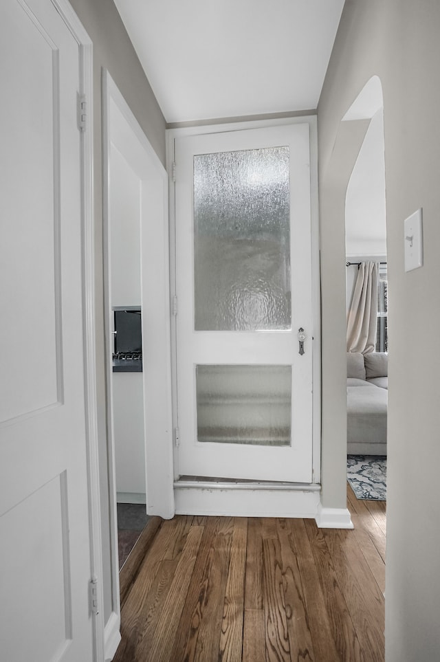 interior space featuring arched walkways, plenty of natural light, and wood finished floors