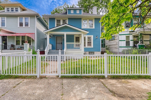 american foursquare style home with a porch, a fenced front yard, and a front lawn