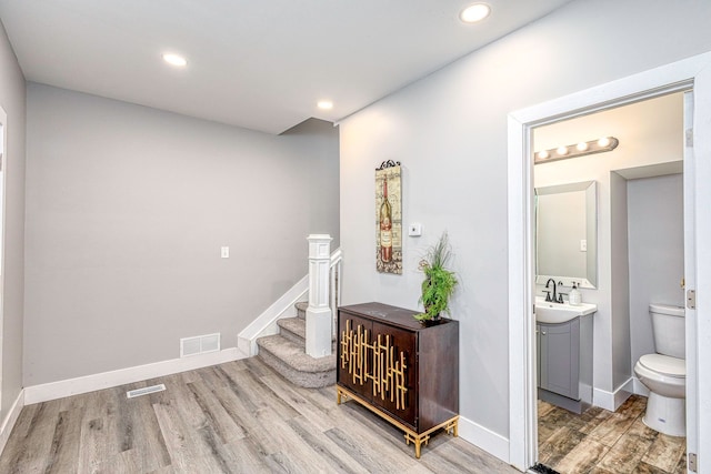 corridor featuring stairway, wood finished floors, visible vents, and baseboards