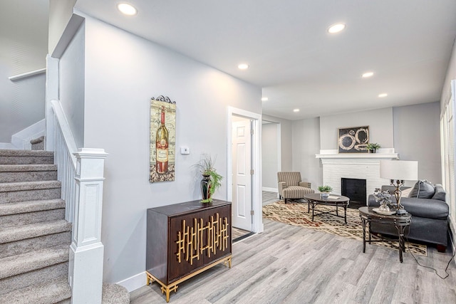 interior space featuring a fireplace, recessed lighting, light wood-type flooring, baseboards, and stairs