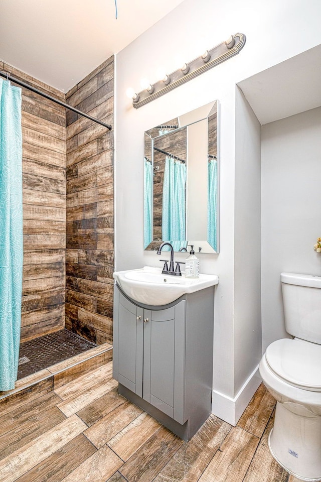 full bath with toilet, a tile shower, wood finished floors, and vanity