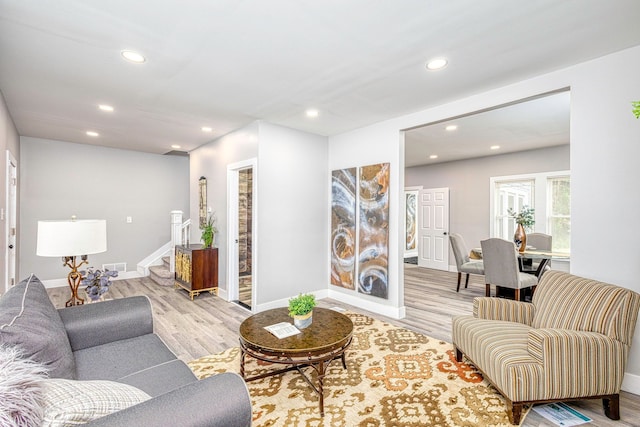 living area with light wood-style flooring, recessed lighting, stairway, and baseboards