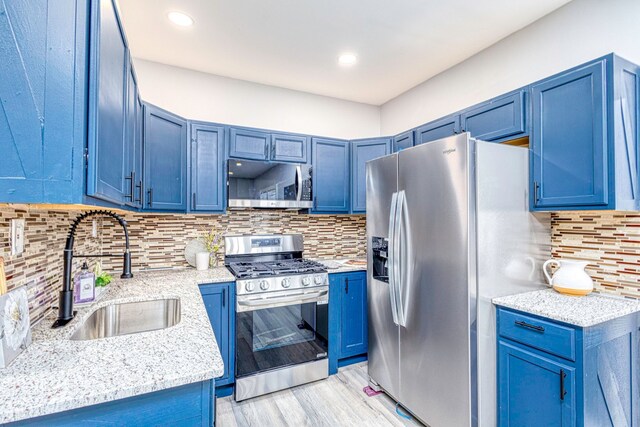 kitchen with blue cabinetry, appliances with stainless steel finishes, and a sink