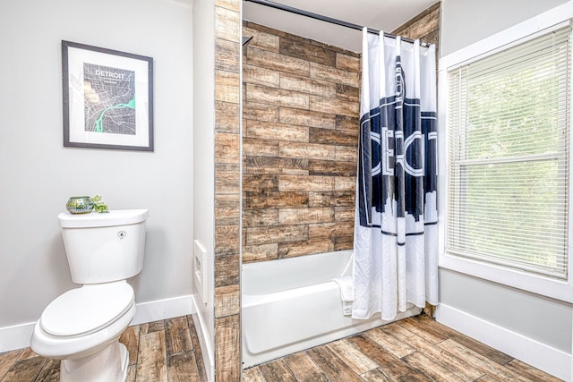 bathroom featuring wood tiled floor, baseboards, shower / tub combo with curtain, and toilet