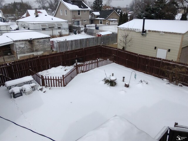 yard layered in snow with a fenced backyard and a residential view