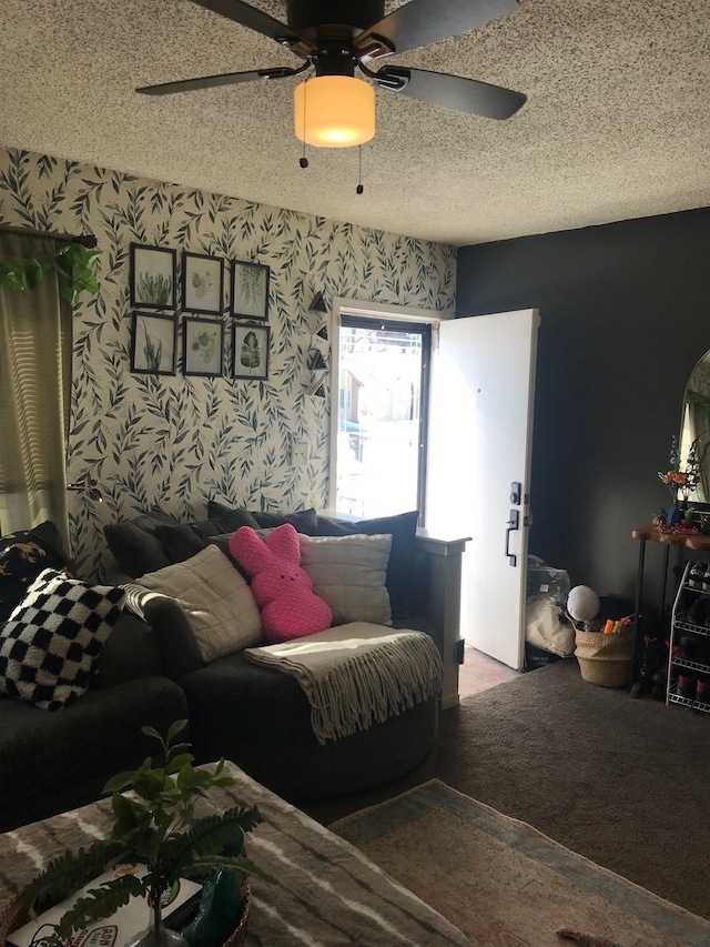 living area featuring carpet floors, wallpapered walls, a ceiling fan, and a textured ceiling