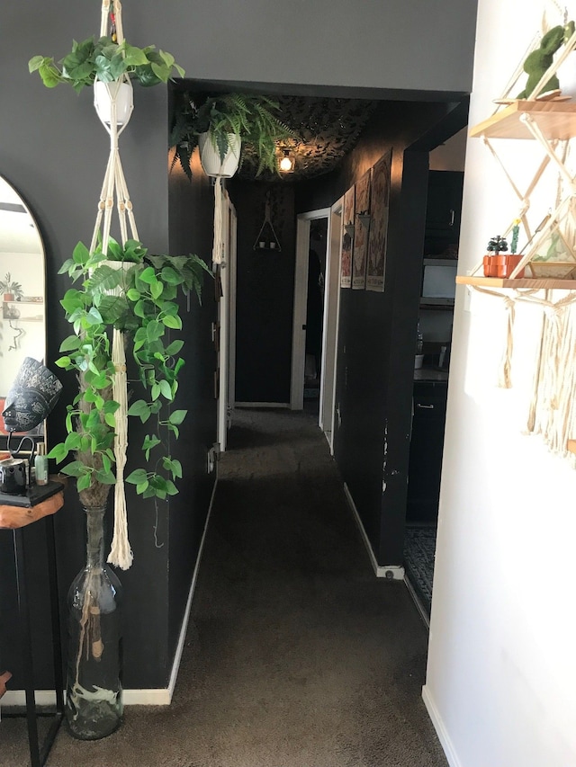 hallway featuring carpet floors and baseboards