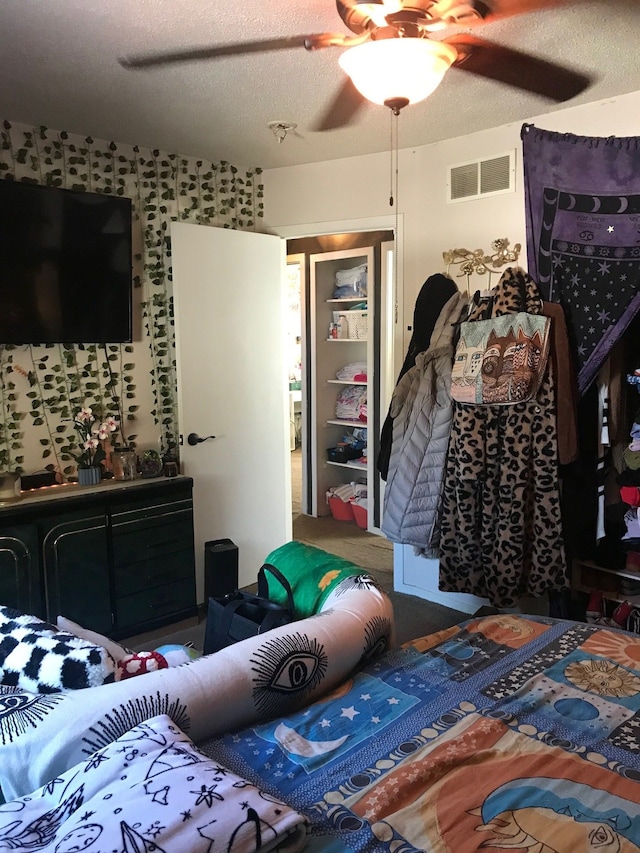 bedroom with ceiling fan, visible vents, and a textured ceiling