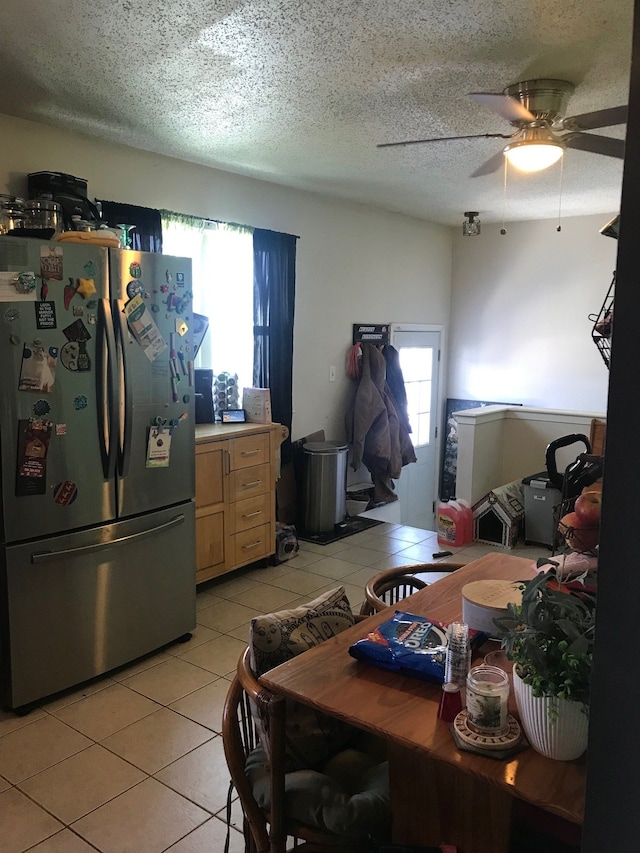 kitchen with light tile patterned floors, light countertops, light brown cabinetry, freestanding refrigerator, and a textured ceiling