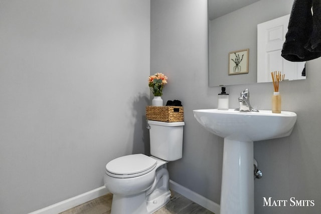 half bath featuring toilet and baseboards