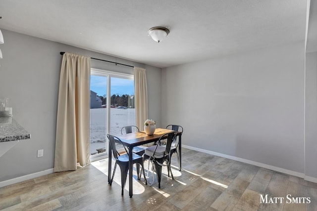 dining room featuring a water view, light wood finished floors, and baseboards