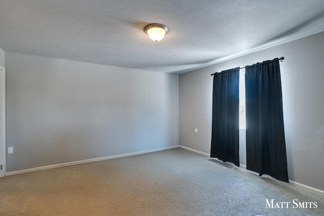 unfurnished room featuring carpet, a textured ceiling, and baseboards