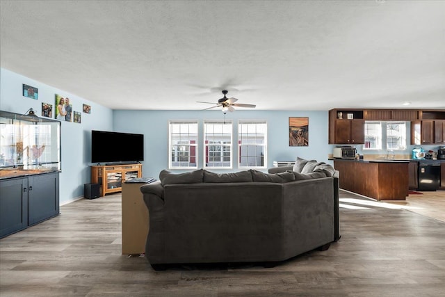 living area featuring a textured ceiling, ceiling fan, and light wood finished floors