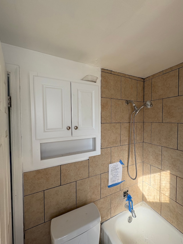 bathroom with tile walls, toilet, and shower / bathtub combination