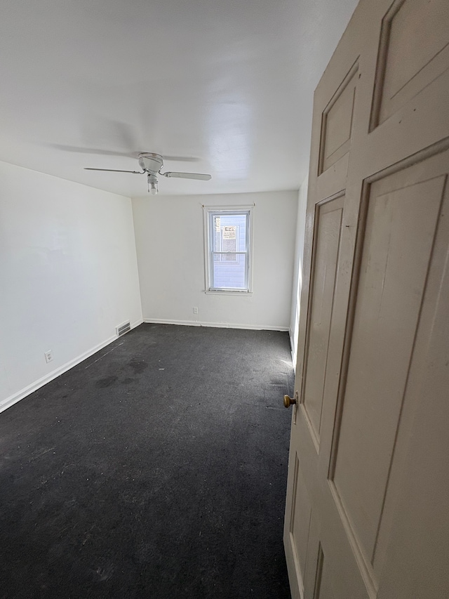 unfurnished bedroom with ceiling fan, dark colored carpet, visible vents, and baseboards