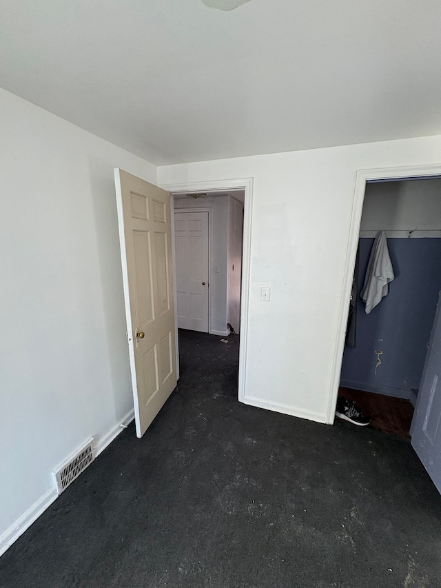 unfurnished bedroom featuring concrete flooring, visible vents, a spacious closet, and baseboards