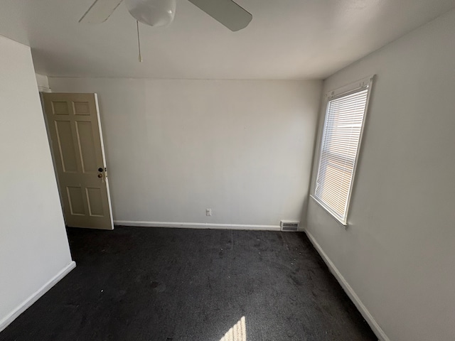 unfurnished room featuring a ceiling fan, dark colored carpet, visible vents, and baseboards