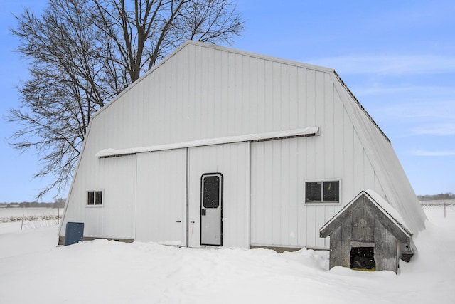 snow covered structure featuring a barn and an outdoor structure