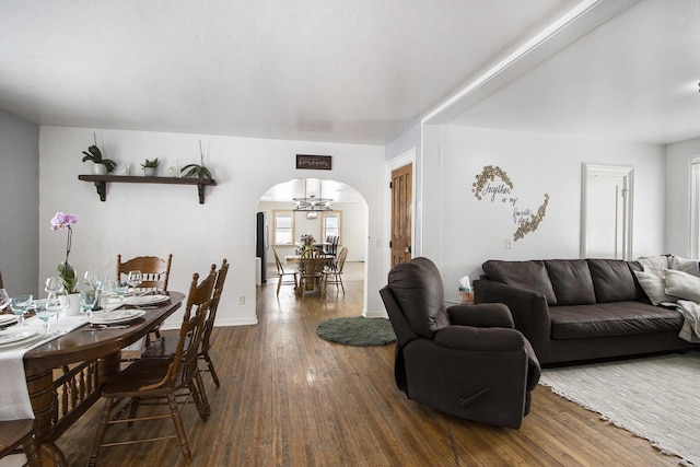 living room featuring arched walkways, dark wood-style floors, and baseboards