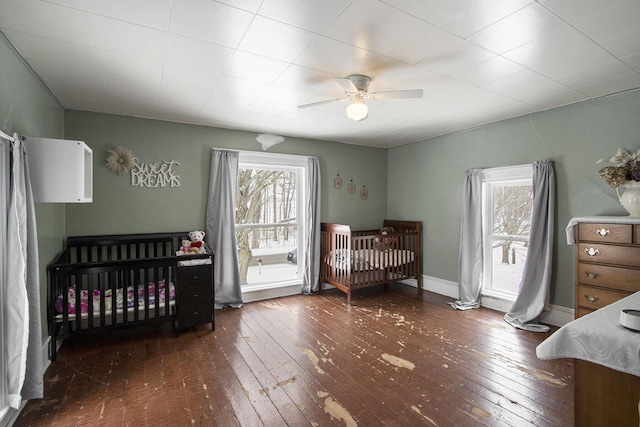 bedroom with baseboards, multiple windows, a ceiling fan, and dark wood-style flooring