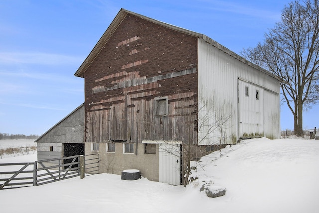 snow covered structure featuring a barn, fence, and an outdoor structure