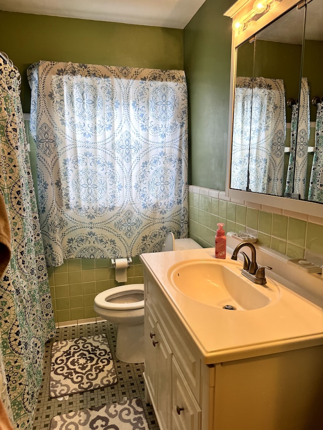 bathroom featuring toilet, tile patterned flooring, tile walls, and vanity