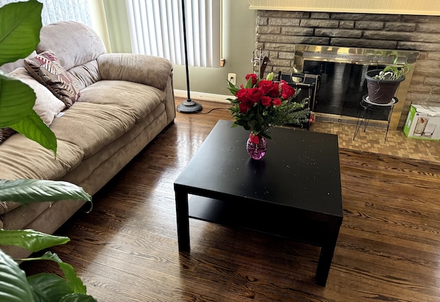 living area with a glass covered fireplace, dark wood finished floors, and baseboards