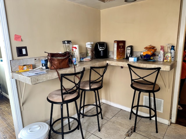 kitchen featuring a peninsula, visible vents, a kitchen breakfast bar, and light countertops