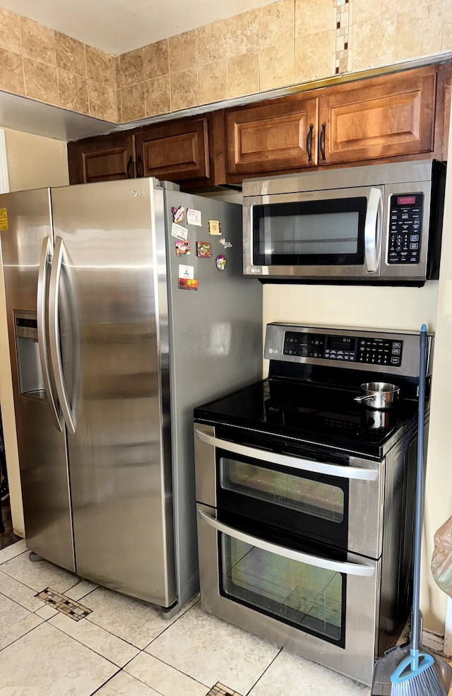 kitchen with appliances with stainless steel finishes, brown cabinets, and light tile patterned floors