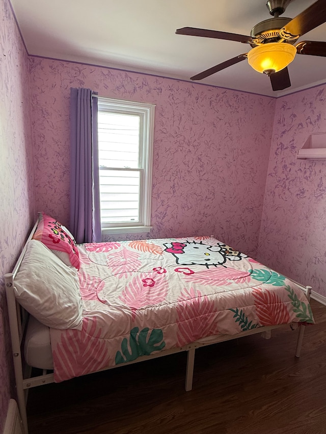 bedroom with wallpapered walls, a ceiling fan, and wood finished floors