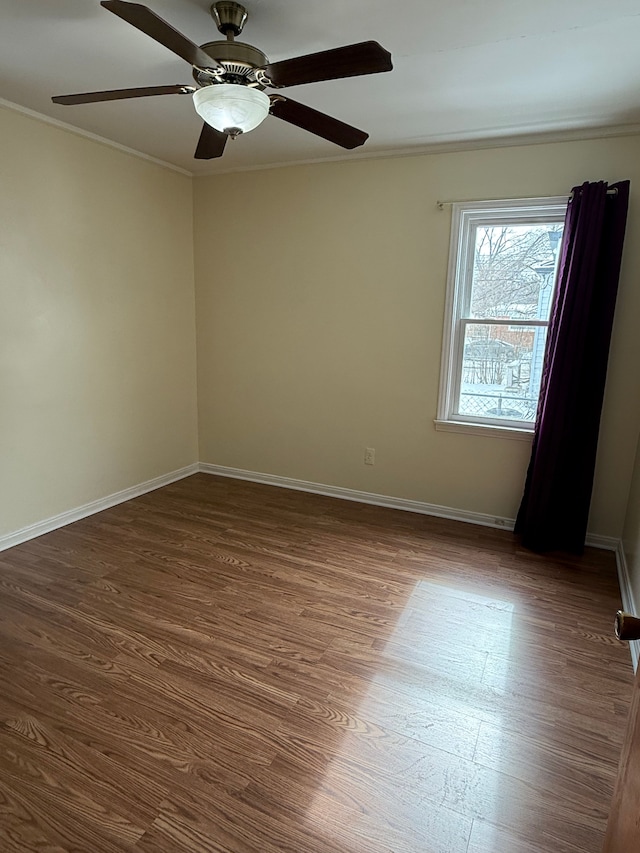 empty room featuring baseboards, dark wood finished floors, and crown molding