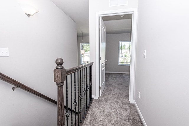 corridor featuring light colored carpet, baseboards, visible vents, and an upstairs landing