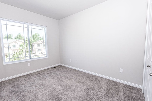 spare room featuring carpet floors, visible vents, and baseboards