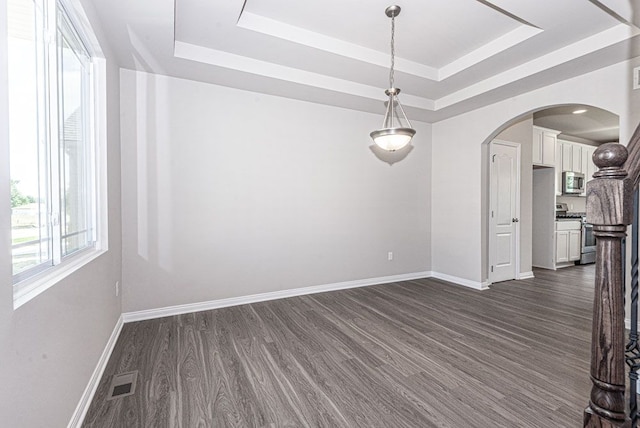 unfurnished dining area featuring arched walkways, a raised ceiling, visible vents, and baseboards