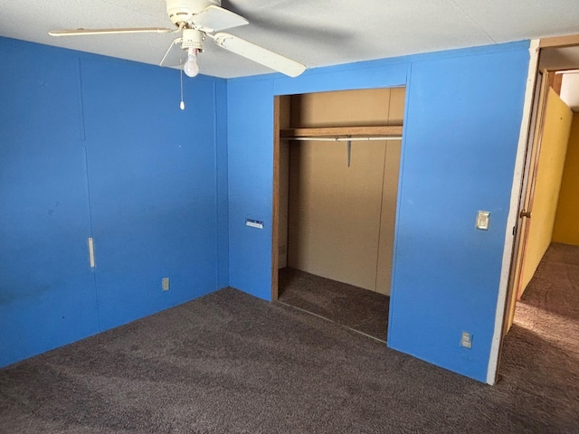 unfurnished bedroom featuring dark colored carpet, a closet, and ceiling fan