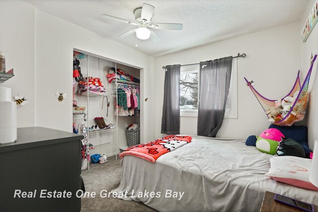 carpeted bedroom with a textured ceiling, a ceiling fan, and a closet