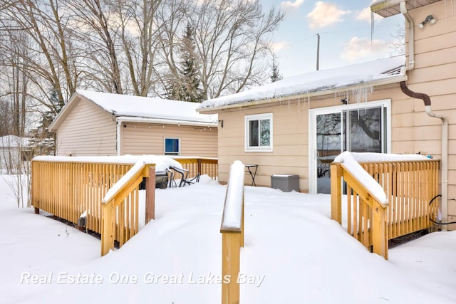 snow covered house featuring a wooden deck