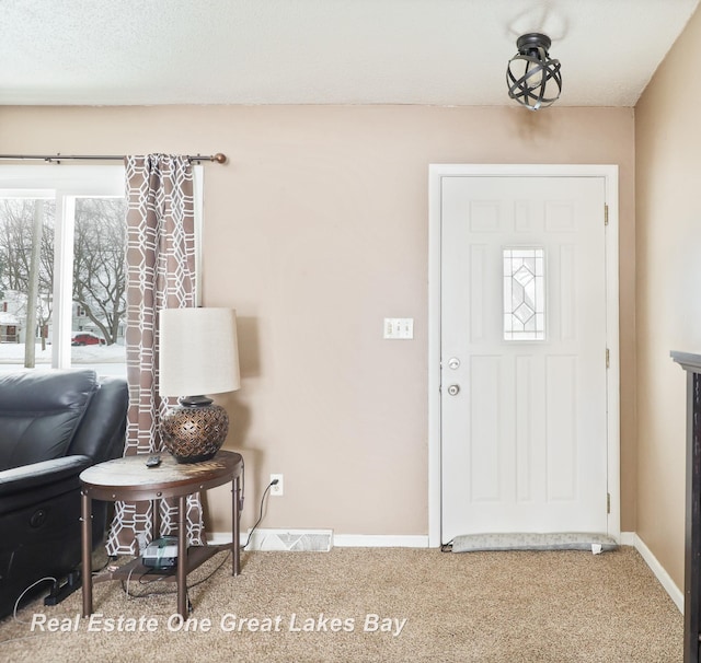 foyer featuring carpet flooring and baseboards