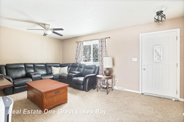 living area featuring light colored carpet, ceiling fan, and baseboards