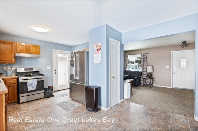 kitchen with light colored carpet, light countertops, appliances with stainless steel finishes, under cabinet range hood, and baseboards