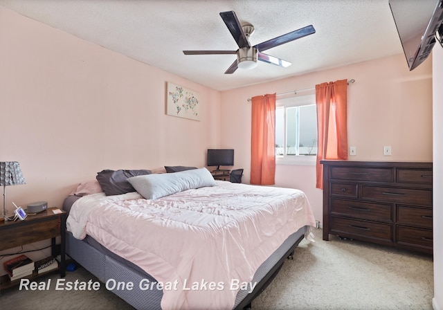 bedroom with light carpet, a textured ceiling, and a ceiling fan