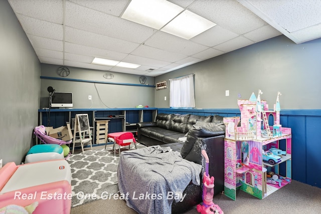 playroom featuring a paneled ceiling, a wainscoted wall, and carpet flooring