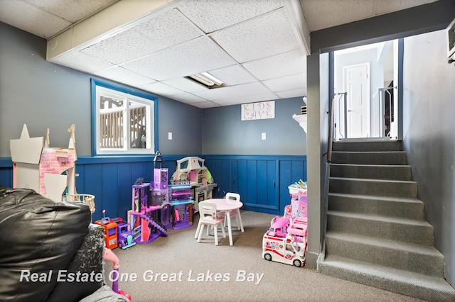 game room featuring carpet floors, a paneled ceiling, and a wainscoted wall