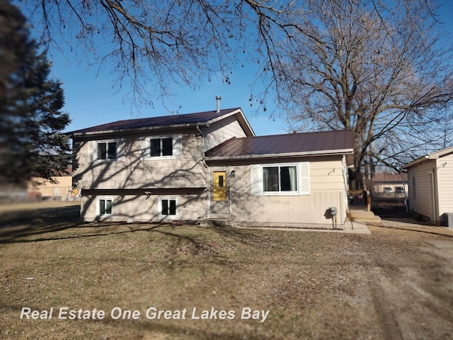 split level home with metal roof and a front lawn