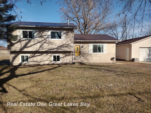 tri-level home featuring an outbuilding, metal roof, and a front yard