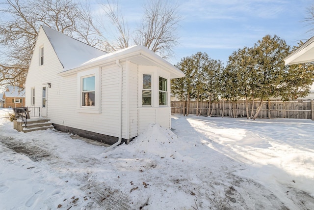 view of snow covered exterior with fence