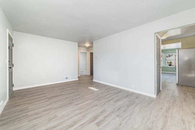 unfurnished room featuring light wood-style floors, visible vents, and baseboards