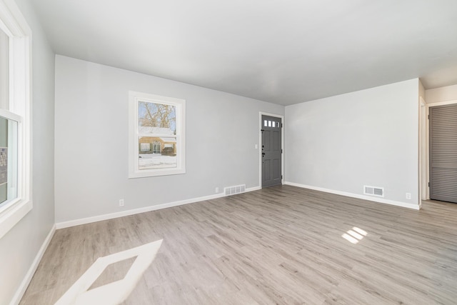 empty room featuring baseboards, visible vents, and light wood finished floors